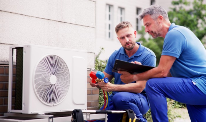 HVAC technicians reviewing an outdoor air conditioning unit in Kaysville, UT