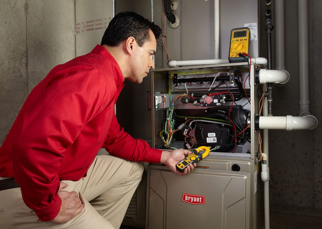 Heating and air conditioning technician servicing an indoor furnace in Kaysville, UT