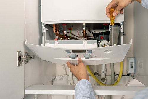 HVAC technician repairing an indoor boiler in Kaysville