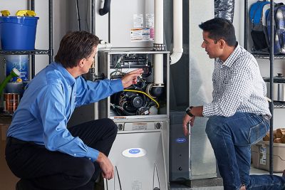 HVAC technician explaining furnace repair and maintenance to a homeowner in Kaysville, UT