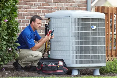 HVAC technician inspecting an outdoor air conditioning unit in Kaysville, UT