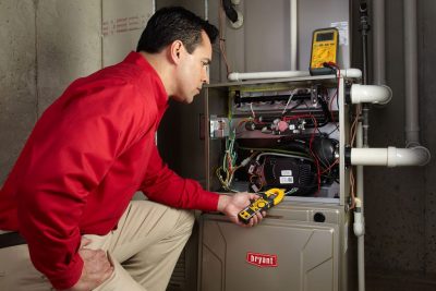 Heating and air conditioning technician servicing an indoor furnace in Kaysville, UT